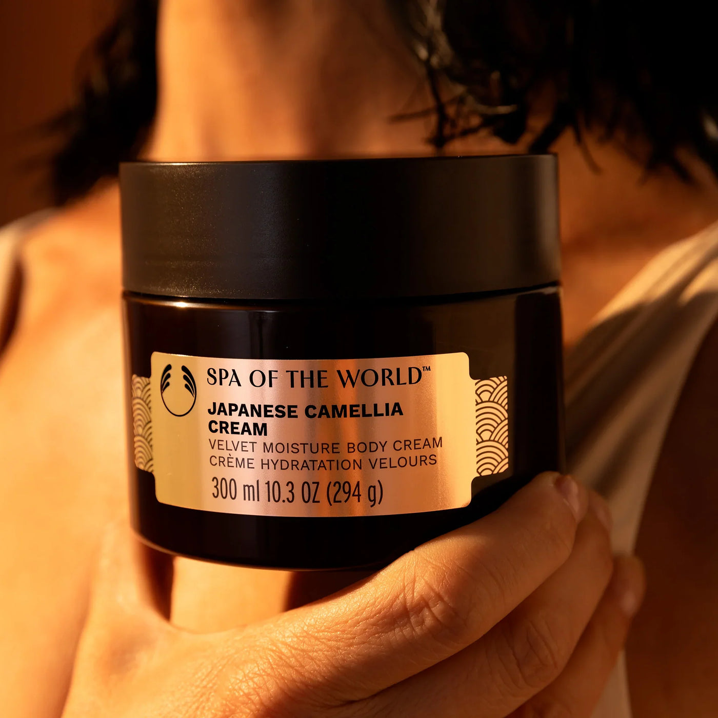 Person holding a jar of The Body Shop's Spa of the World Japanese Camellia Cream