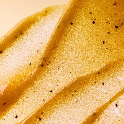 Close-up of Refreshing Passionfruit gel body scrub spread out on a surface with brown passionfruit seeds speckled throughout